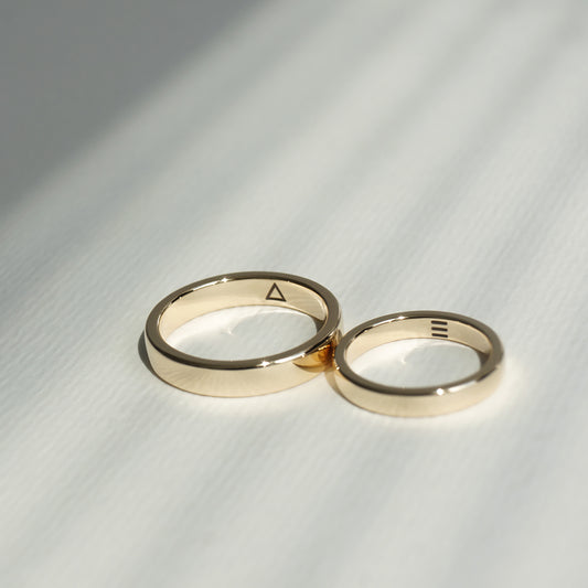 Two minimalist wedding rings in yellow gold with laser engravings.