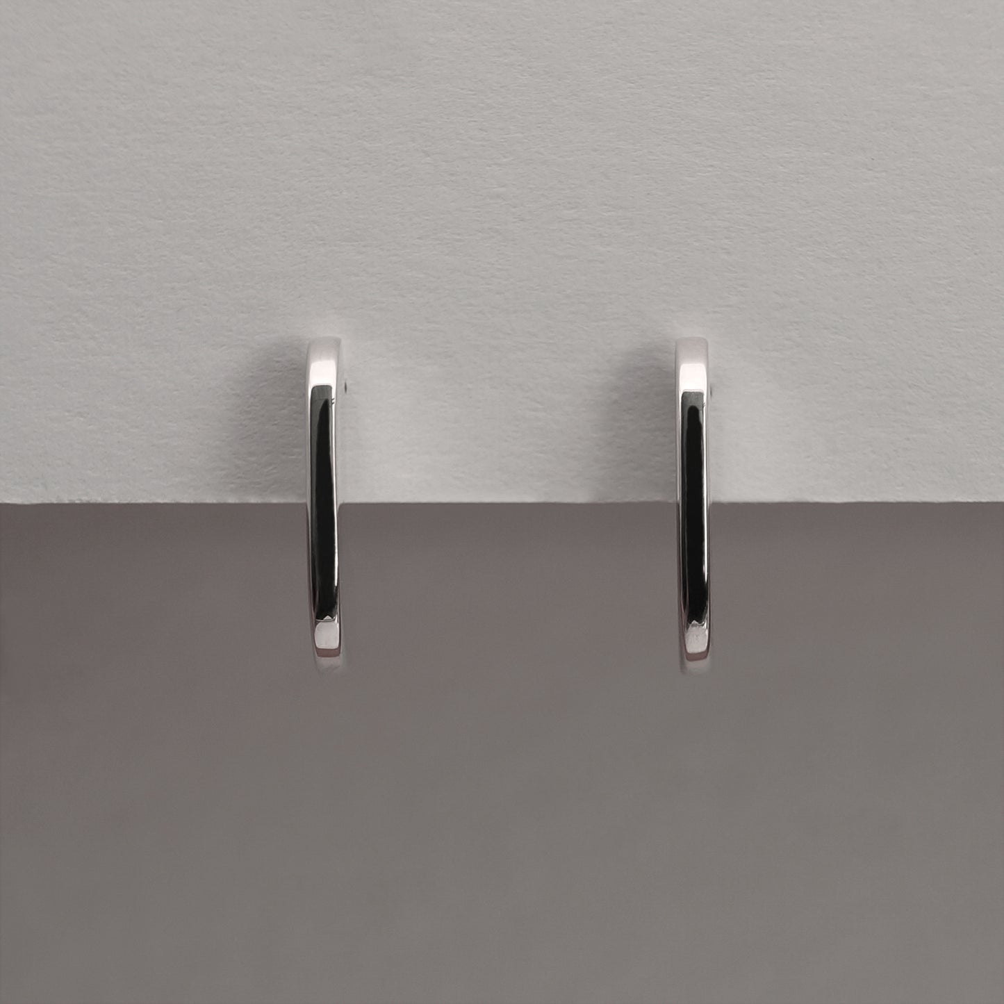 A front view of a pair of silver earrings with an organic shape and minimalist design.