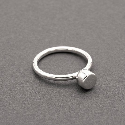 A slight side view of a silver ring with a minimalist design and a half-capsule element.