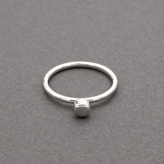 A front view of a silver ring with a minimalist design and a small half-capsule element.