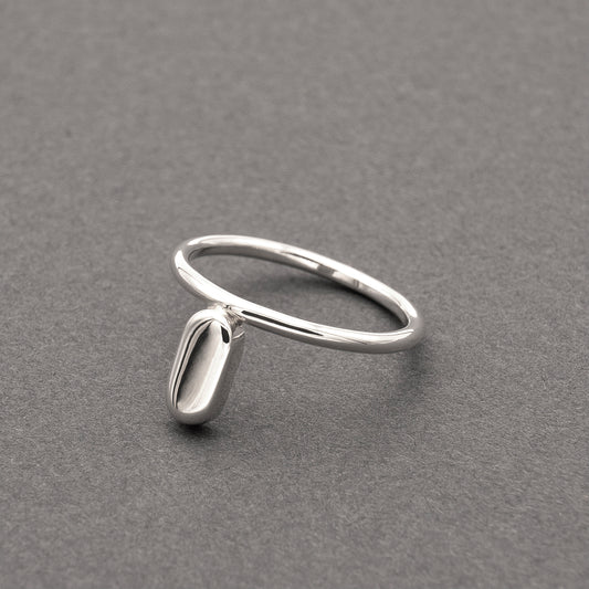 A slight side view of a silver ring with a minimalist design and a flat capsule element.