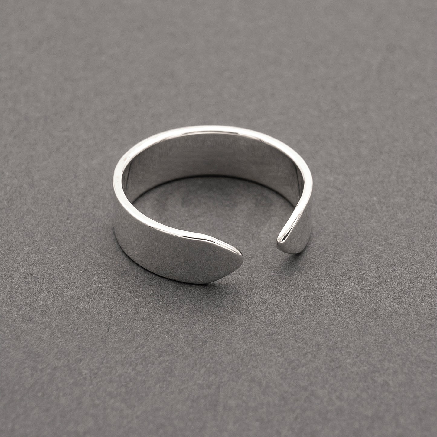 A slight side view of a minimalist design wide band ring in silver.
