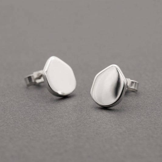 A pair of silver earrings with an organic shape and minimalist design.