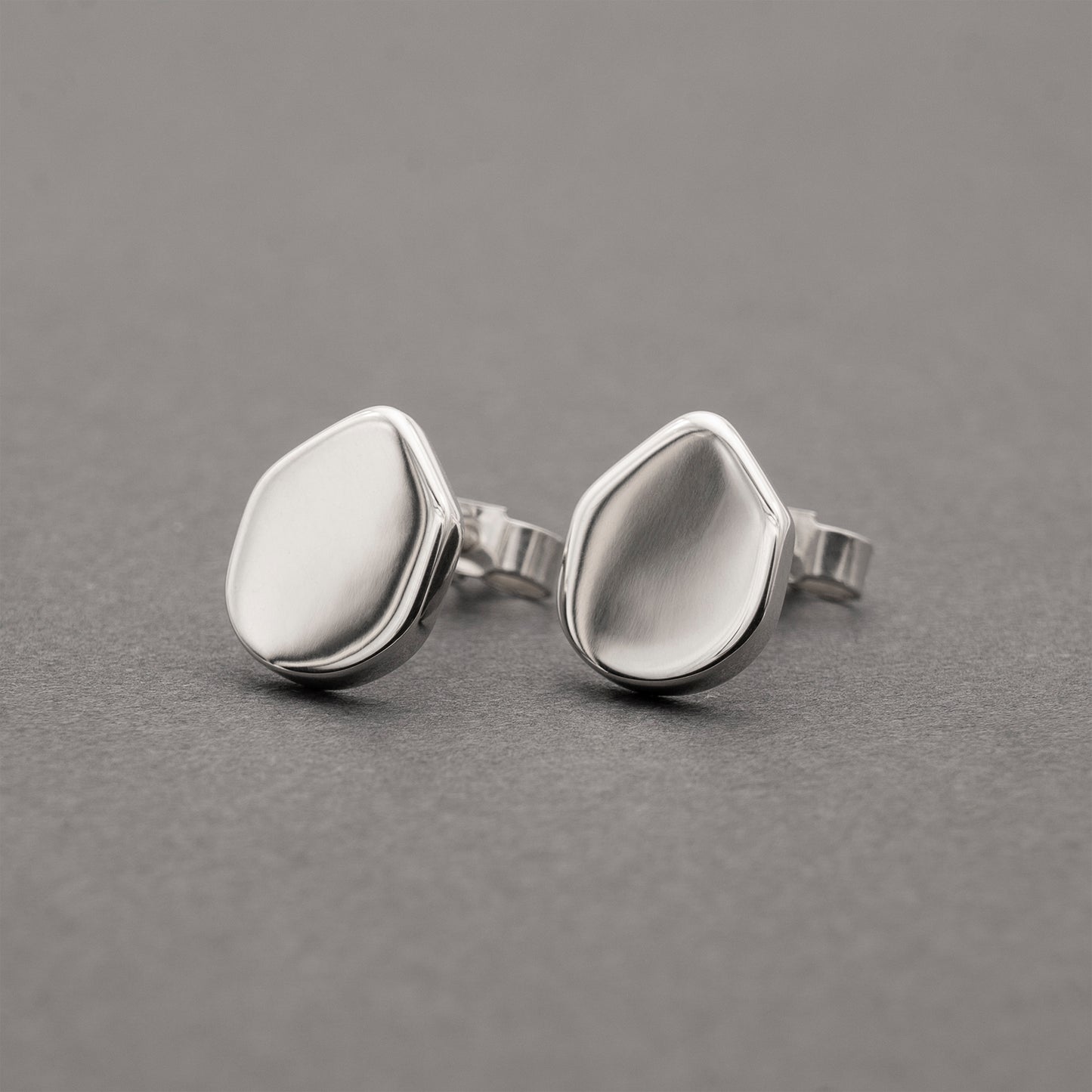 A pair of silver earrings with an organic shape and minimalist design.