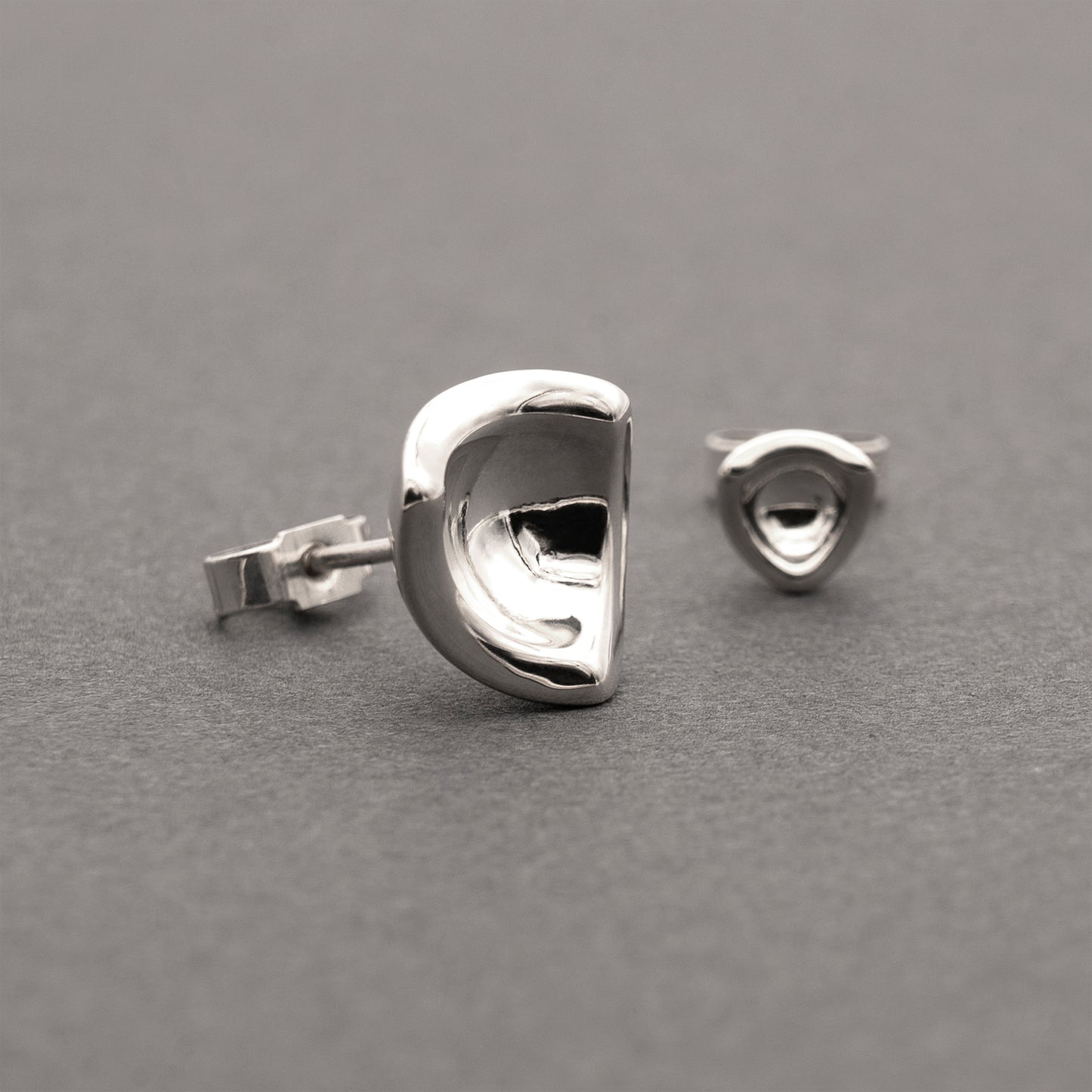 Two silver earrings in a minimalist, organic shape.