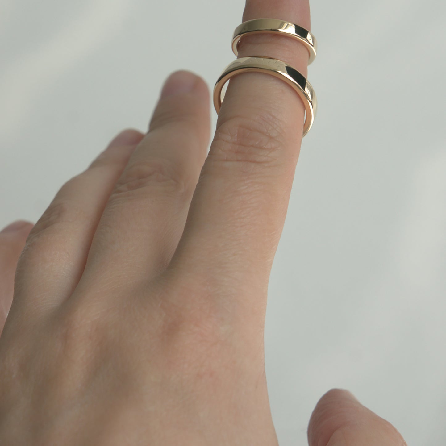 Two minimalist wedding rings in yellow gold on a woman's finger.