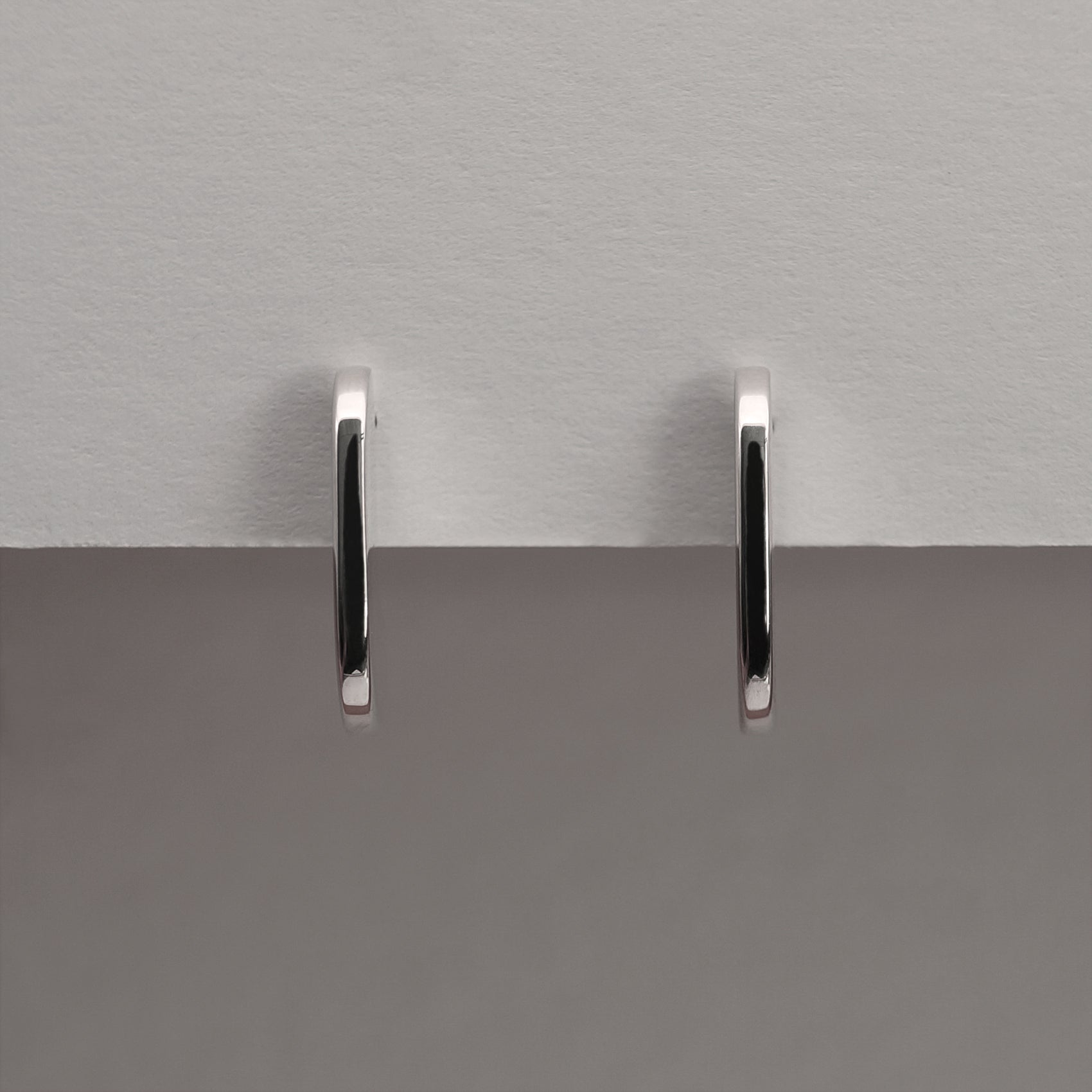 A front view of a pair of silver earrings with an organic shape and minimalist design.