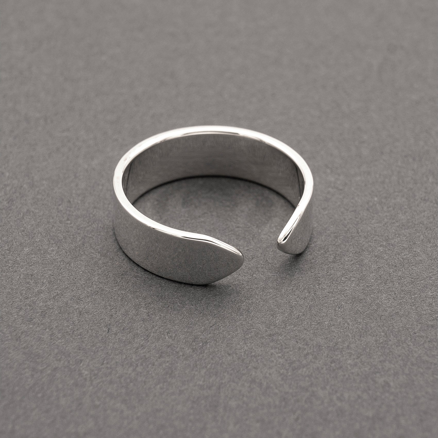 A slight side view of a minimalist design wide band ring in silver.