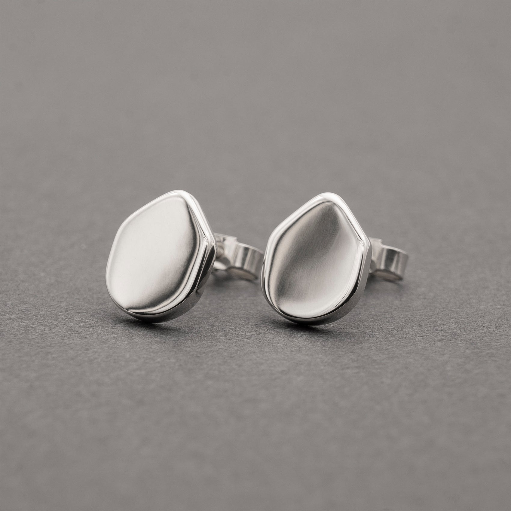 A pair of silver earrings with an organic shape and minimalist design.
