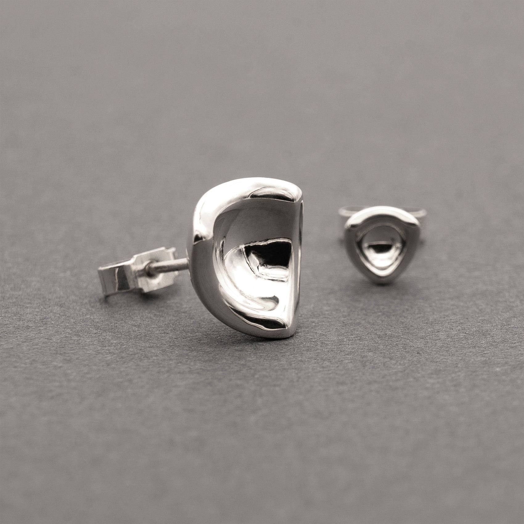 Two silver earrings in a minimalist, organic shape.
