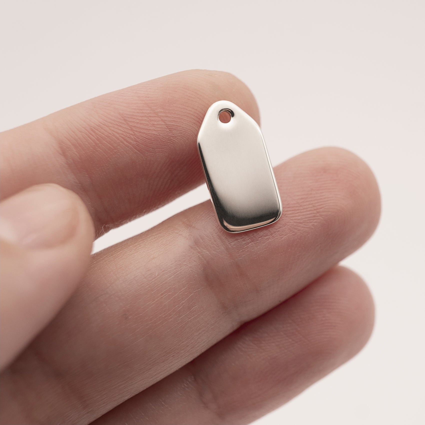 A close-up of a minimalist silver earring backplate in a woman's hand.